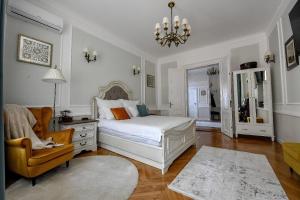 a bedroom with a bed and a chair and a chandelier at Casa Barițiu in Braşov