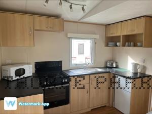a kitchen with a stove and a microwave at Caravan Holiday on Haven site in Cleethorpes