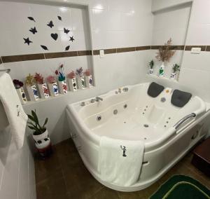a white bath tub in a bathroom with butterflies on the wall at Loreto hotel in Latacunga