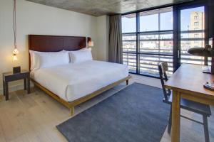 a bedroom with a bed and a desk and a large window at Boro Hotel in Queens