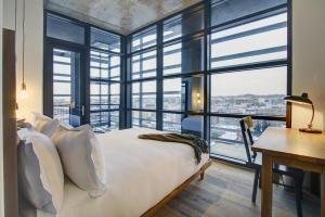 a bedroom with a bed and a desk and windows at Boro Hotel in Queens