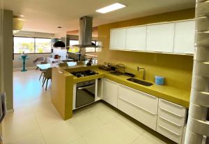 a kitchen with white cabinets and a yellow wall at Barra Bali, com incrível vista para o mar! - Destino BSM 209 in Barra de São Miguel