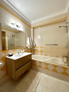 een badkamer met een bad, een wastafel en een douche bij Sun & Wave Apartment in Peniche