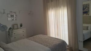 een slaapkamer met een bed, een ladekast en een raam bij La Casilla de Nerja in Nerja