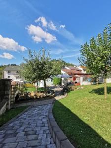 a stone walkway in a yard with trees and a house at Ubytovanie v súkromí Zelený dom in Vyšné Ružbachy