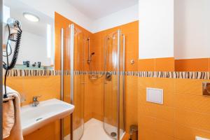 a bathroom with orange walls and a shower and a sink at Penzion a Restaurant Barbora in Kutná Hora