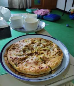 uma pizza num prato numa mesa em Mulberry Guest House F-10 em Islamabad