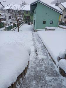 a sidewalk covered in snow next to a house at Ubytovanie v súkromí Zelený dom in Vyšné Ružbachy