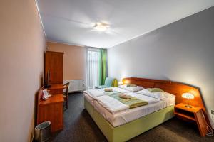 a bedroom with a large bed and a desk and a chair at Penzion a Restaurant Barbora in Kutná Hora