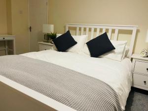 ein weißes Bett mit zwei schwarzen Kissen darauf in der Unterkunft Hotel 3H in Stafford