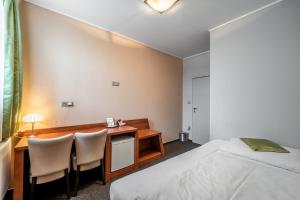a bedroom with a desk and a bed and a table and chairs at Penzion a Restaurant Barbora in Kutná Hora
