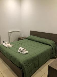 sypialnia z zielonym łóżkiem i ręcznikami w obiekcie Terrazza famà w Katanii