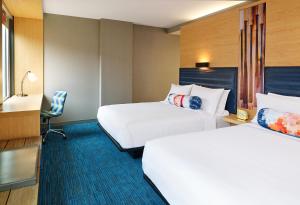 a hotel room with two beds and a chair at Aloft by Marriott Louisville Downtown in Louisville