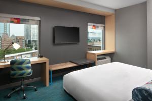 a hotel room with a bed and a desk and a tv at Aloft by Marriott Louisville Downtown in Louisville