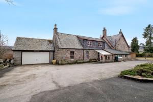 an old stone house with a garage in a driveway at Creag Meggan in Ballater