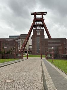 a large metal structure in front of a building at Ein Nachbar des Unesco-Weltkulturerbes Zeche Zollverein! GE2R in Essen