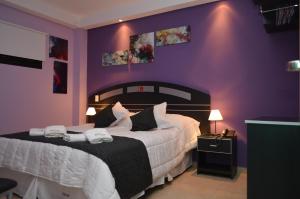 een slaapkamer met een groot bed met paarse muren bij Mercer Hostal in San Miguel de Tucumán