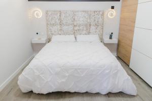 un letto bianco in una stanza con due tavoli bianchi di Apartamento VillaRo a Cartes