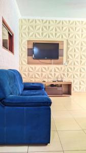 un sofá azul en la sala de estar con TV de pantalla plana en Casa com piscina no centro de Maragogi pertinho da praia!, en Maragogi