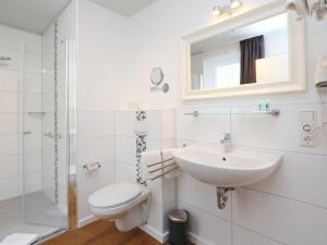 a bathroom with a sink and a toilet and a mirror at Apartment in Lissendorf with a paid private sauna in Lissendorf