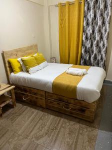 um quarto com uma cama de madeira e uma cortina amarela em Fully Furnished 2br Apartment King'ong'o Nyeri - Youngsky em Nyeri