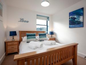 una camera da letto con un grande letto con lenzuola bianche e cuscini blu di Cove View a Porthcurno
