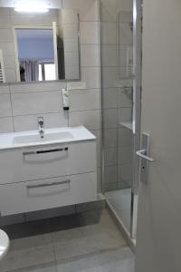 een witte badkamer met een wastafel en een douche bij Hôtel Restaurant Le Saint Clément in Saint-Clement-sur-Valsonne