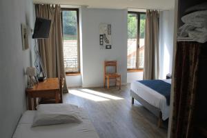 a bedroom with two beds and a desk and windows at Hôtel Restaurant Le Saint Clément in Saint-Clement-sur-Valsonne