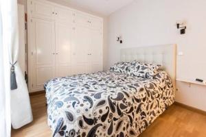 een slaapkamer met een bed met een zwart-wit dekbed bij Luminoso Apartamento en Lavapiés-Tirso de Molina in Madrid