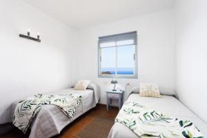 two beds in a room with a window at EDEN RENTALS Atogo Cozy Apartment in Granadilla de Abona