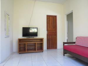 ein Wohnzimmer mit einem Fernseher auf einem Holzschrank in der Unterkunft Casa com Piscina e Churrasqueira perto da Praia in Pontal do Paraná