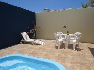 eine Terrasse mit einem Tisch, Stühlen und einer Badewanne in der Unterkunft Casa com Piscina e Churrasqueira perto da Praia in Pontal do Paraná