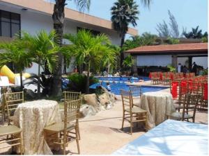 a group of tables and chairs next to a swimming pool at Hotel Poza Rica Inn in Poza Rica de Hidalgo