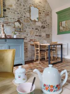 eine Küche mit einem Tisch, einer Teekanne und Stühlen in der Unterkunft Le gite du pré dorė in Bonneville-la-Louvet