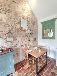 una mesa y sillas en una habitación con una pared de piedra en Le gite du pré dorė, en Bonneville-la-Louvet