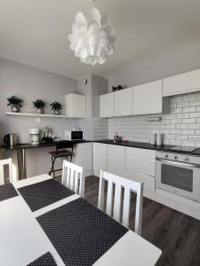 a kitchen with white cabinets and a table and chairs at Sweet family apartments Hamina in Hamina