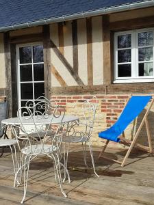 una mesa y sillas en una terraza con un edificio en Le gite du pré dorė, en Bonneville-la-Louvet