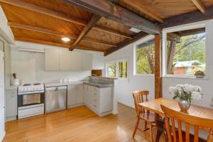 a kitchen with white cabinets and a wooden table at Holiday Chalet in Arthurs Pass in Arthur's Pass