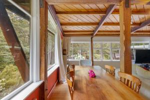 a dining room with a table and chairs and windows at Holiday Chalet in Arthurs Pass in Arthur's Pass