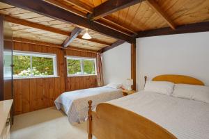 a bedroom with two beds in a room with wooden walls at Holiday Chalet in Arthurs Pass in Arthur's Pass