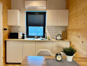 a kitchen with white cabinets and a table with a clock at Ptasia Zatoka Sarbinowo in Sarbinowo