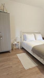 a bedroom with a white bed and a white cabinet at Vita Nova in Hippolytushoef