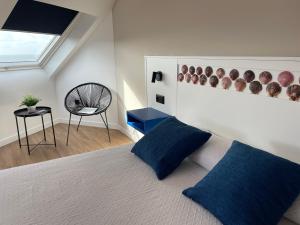 a bedroom with a bed with blue pillows and a chair at Hotel Playa de Sardiñeiro in Finisterre