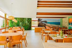 um restaurante com mesas e cadeiras de madeira e o oceano em Mana Beach Experience By Mai em Porto de Galinhas