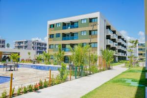un edificio de apartamentos con una pista de tenis enfrente en Mana Beach Experience By Mai en Porto De Galinhas