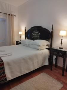 - une chambre avec un lit avec une tête de lit noire et 2 tables dans l'établissement Mont' Sobro House Rooms, à Évora