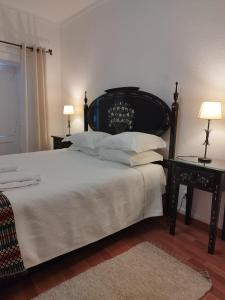 1 Schlafzimmer mit einem Bett mit einem schwarzen Kopfteil und 2 Tischen in der Unterkunft Mont' Sobro House Rooms in Évora