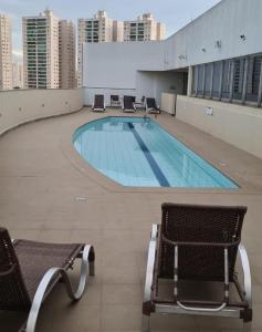 a swimming pool on top of a building with chairs at Lindíssimo Flat em Taguatinga. Conforto, tranquilidade e paz em um ambiente perfeito. in Brasilia