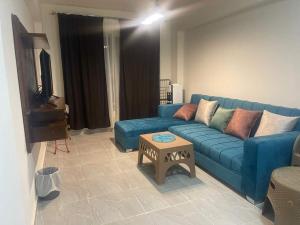 a living room with a blue couch and a table at One bedroom apartment at marina city portghalib in Port Ghalib