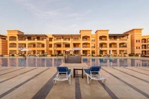 um edifício com duas cadeiras e uma mesa em frente a uma piscina em One bedroom apartment at marina city portghalib em Port Ghalib